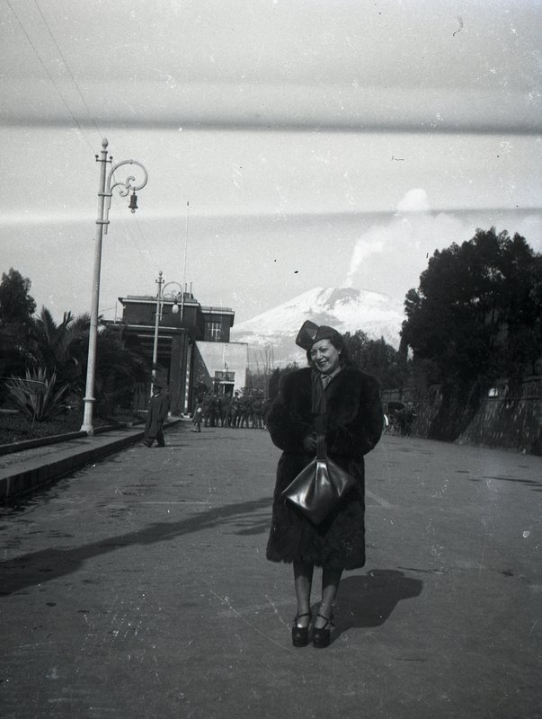 A b&w picture from the 20th century, a lady with volcano Vesuvius in the background